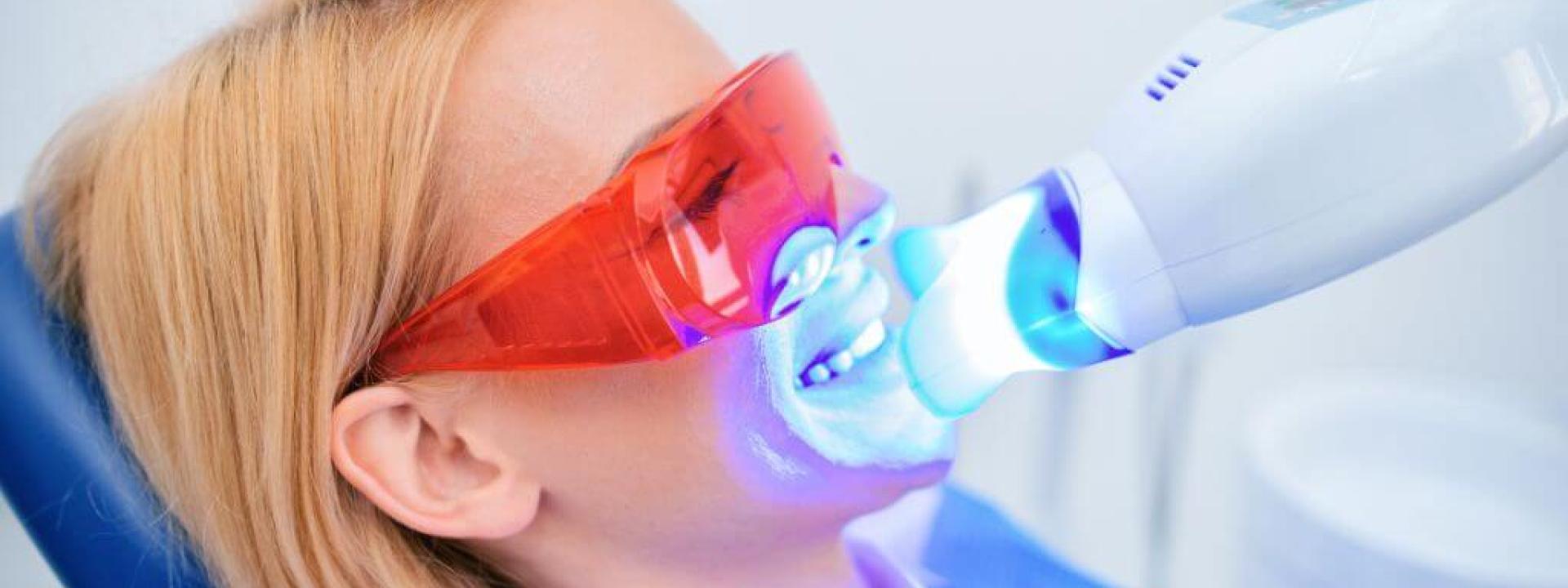 Woman having professional teeth whitening done at the dentists office