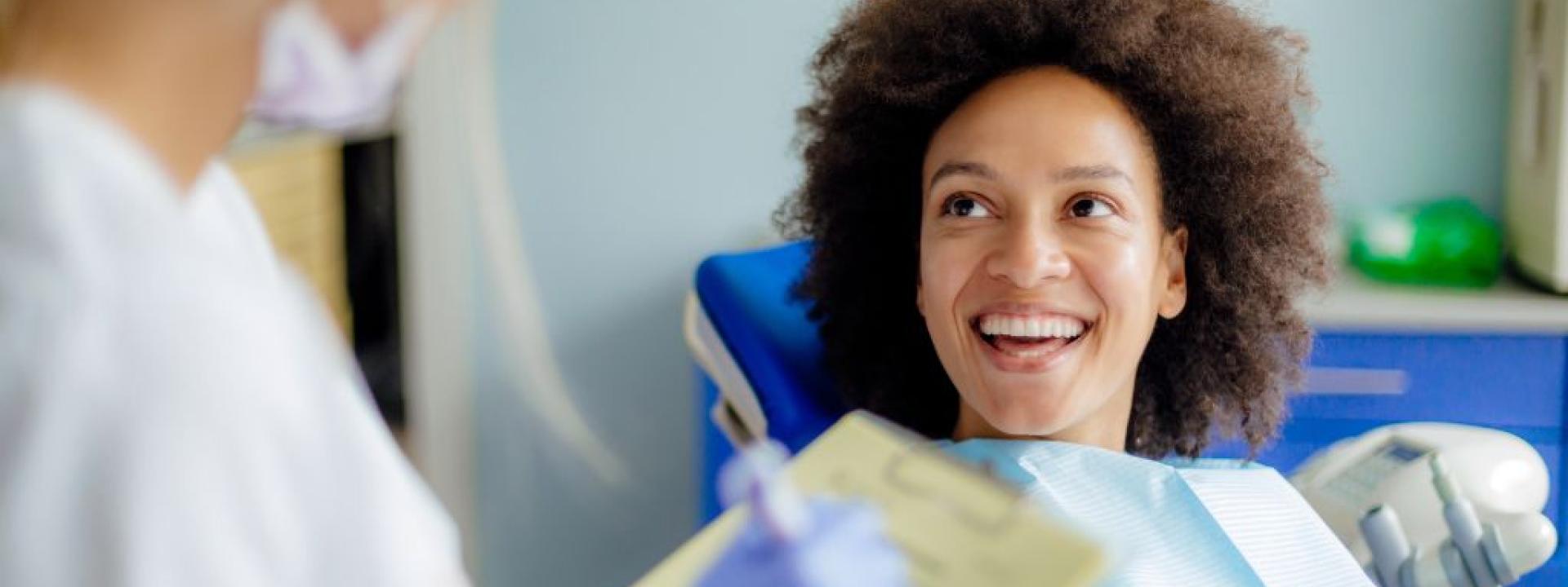 Woman smiling in dental chair during CEREC dental crowns consultation