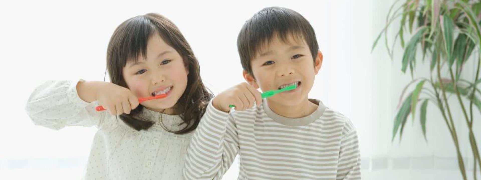 Two young children brushing their teeth for good childhood oral health