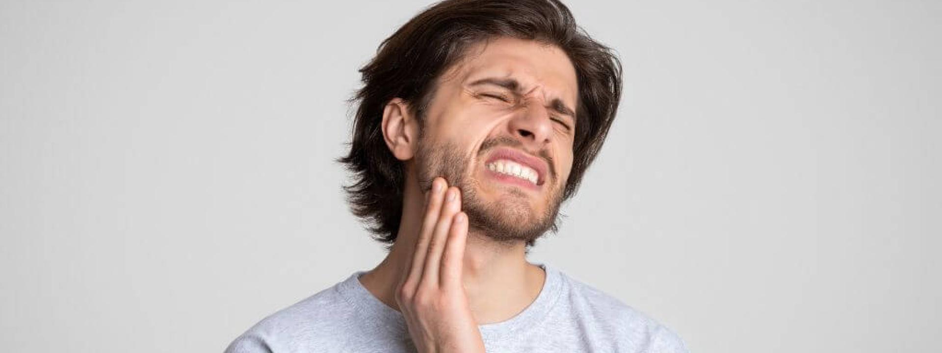 Man holding jaw suffering from TMJ pain